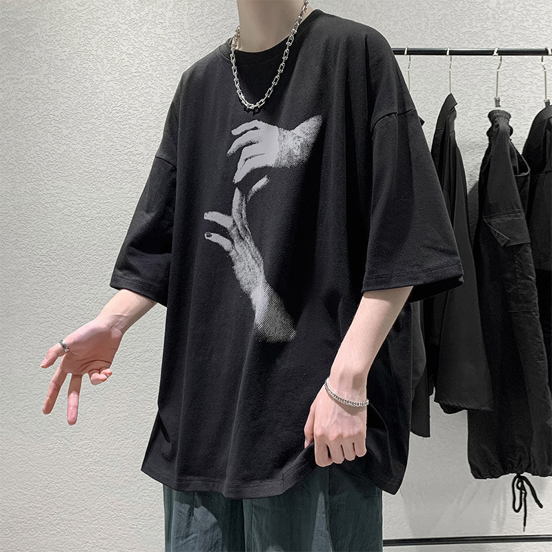 Black oversized t-shirt with a reaching-hands graphic on the front, worn by a model, front view