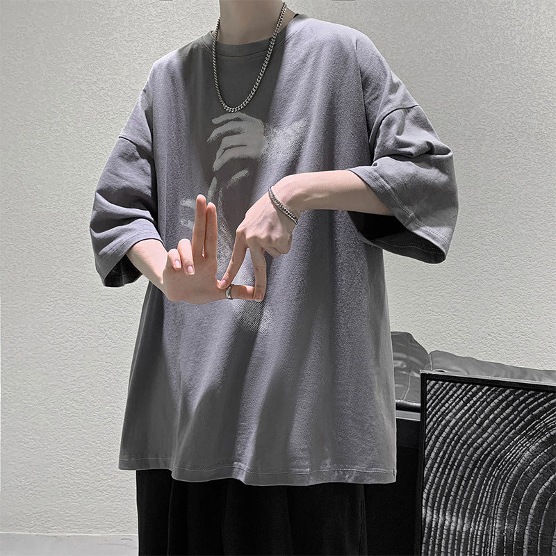 Grey oversized t-shirt with a reaching-hands graphic on the front, worn by a model, front view