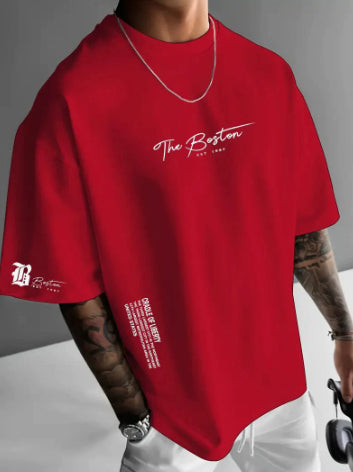 Red oversized t-shirt with a script print on the chest and a small sleeve emblem, worn by a model, front view
