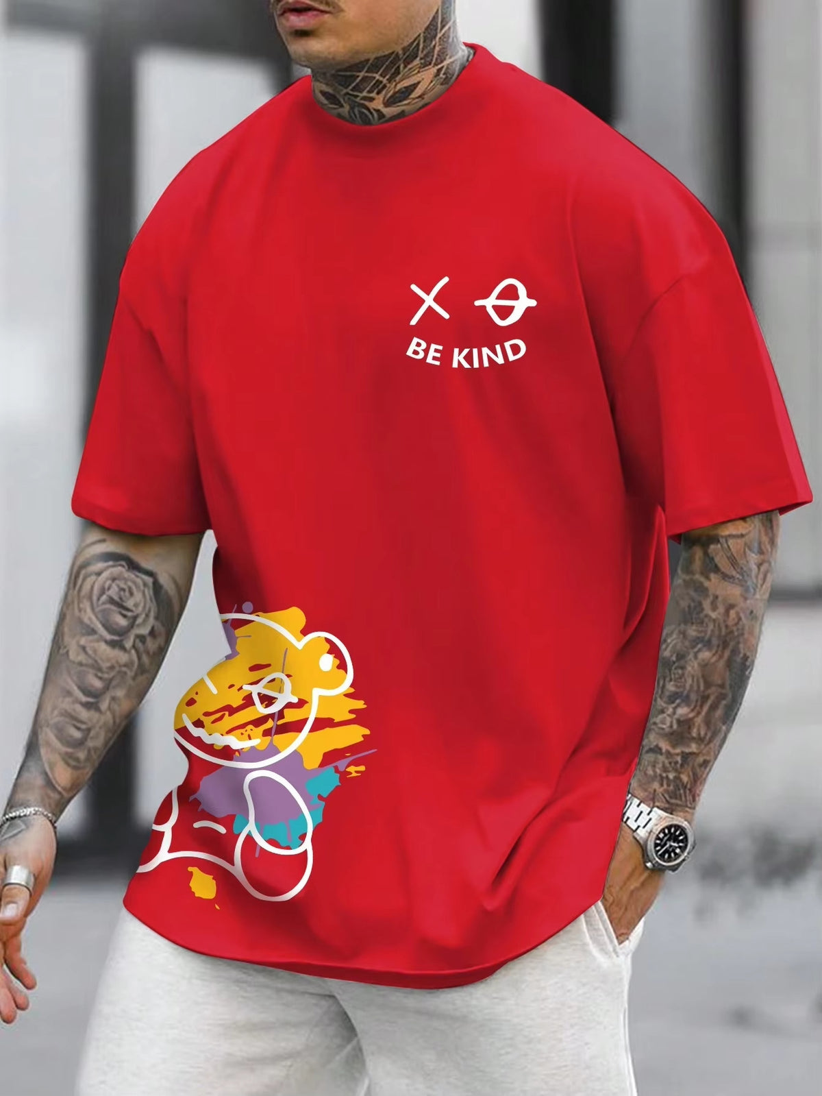 Red t-shirt with a cartoon bear graphic at the hem and small text on the chest, worn by a model, front view