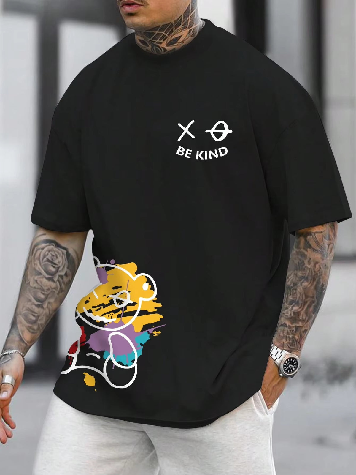 Black t-shirt with a cartoon bear graphic at the hem and small text on the chest, worn by a model, front view