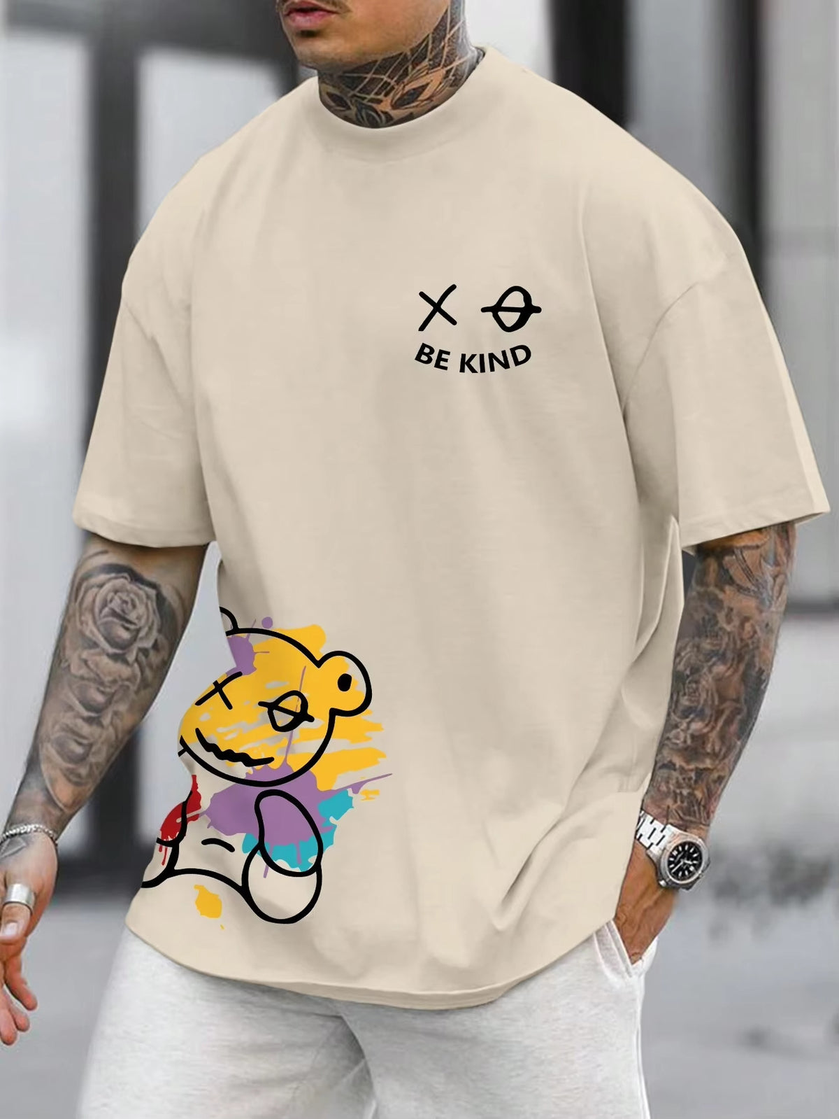 Cream t-shirt with a cartoon bear graphic at the hem and small text on the chest, worn by a model, front view