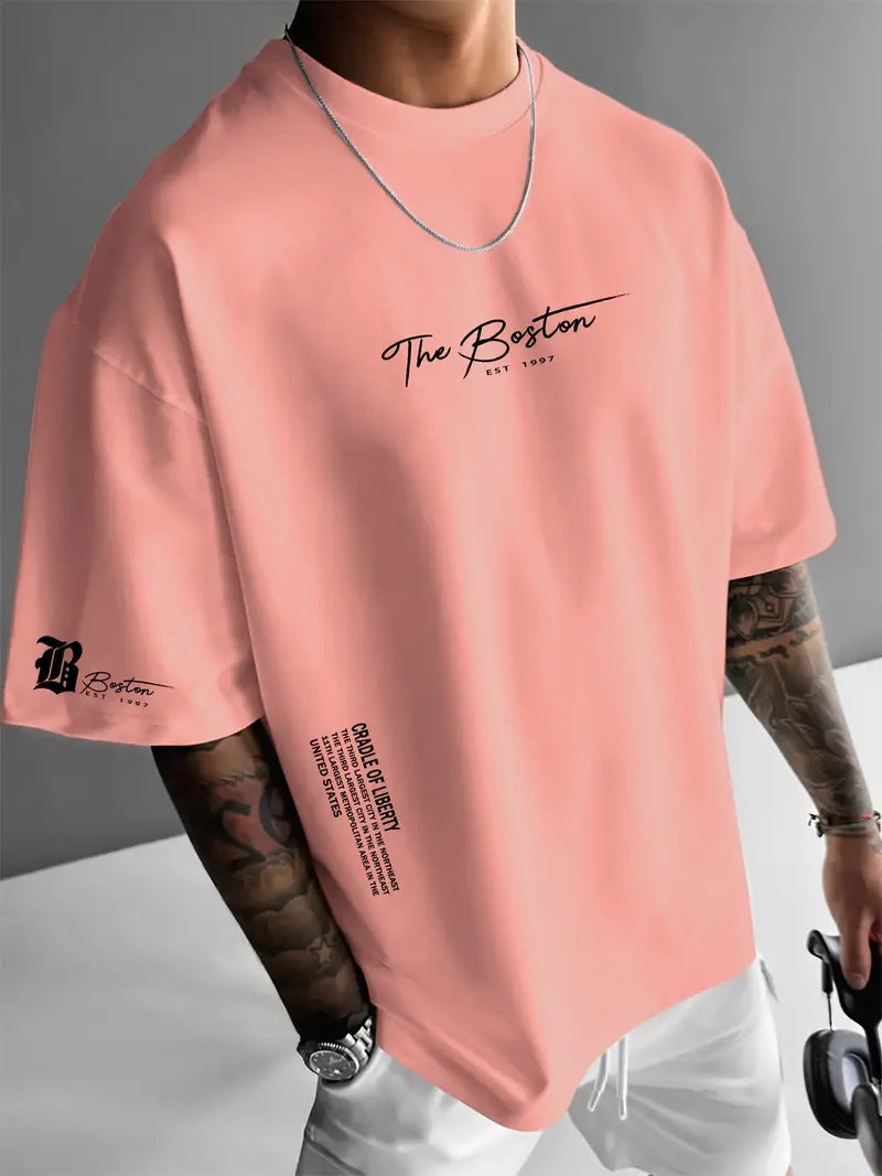 Coral Pink oversized t-shirt with a script print on the chest and a small sleeve emblem, worn by a model, front view